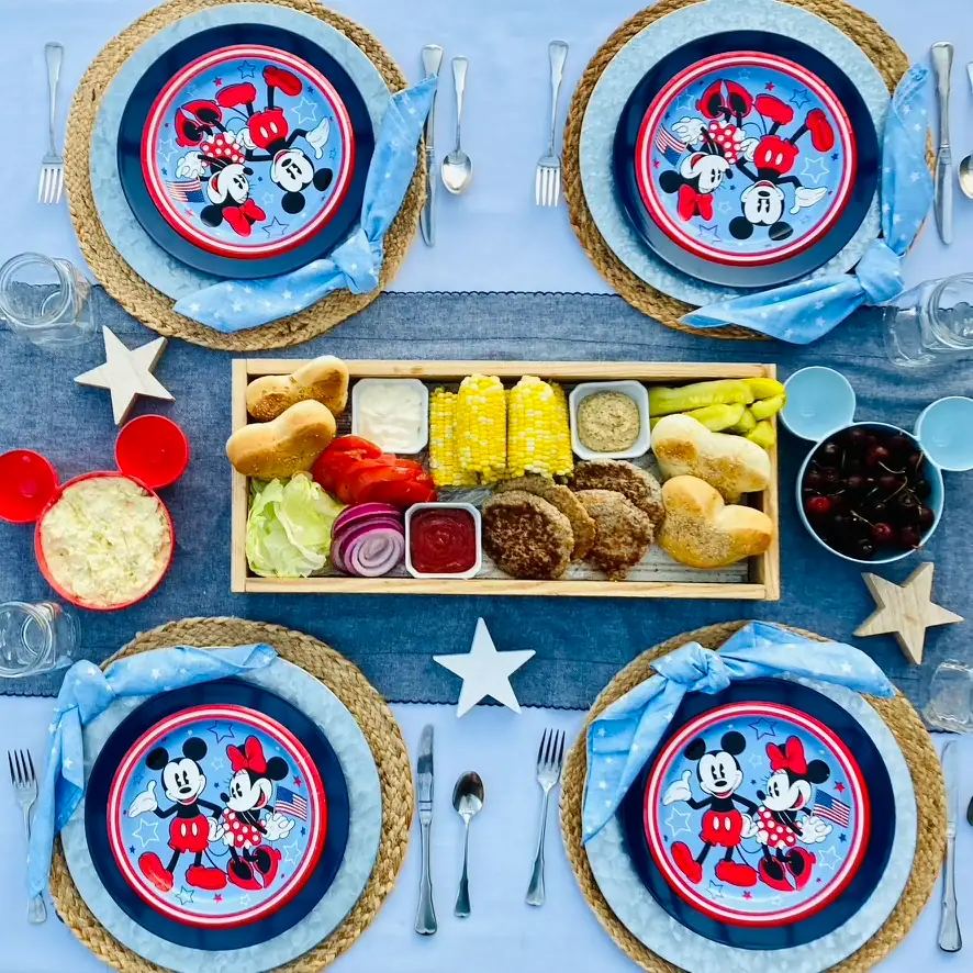 Mickey Burger Board with Mickey-shaped buns, burger patties, corn on the cob, lettuce, tomato, red onion, pickles, mayo, and mustard arranged on a long farmhouse tray for a Disney Patriotic Farmhouse BBQ