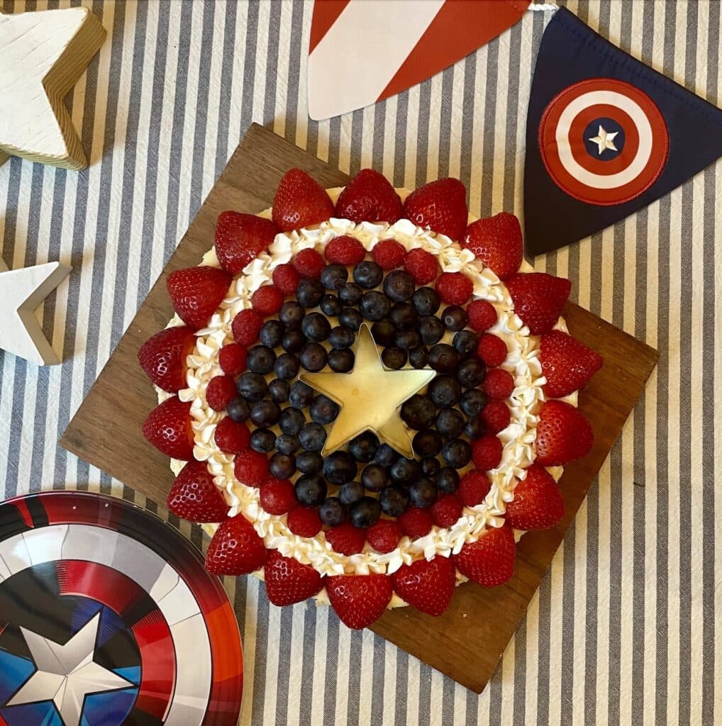 Center of Captain America Shield Cheesecake showing a whipped cream star surrounded by fresh blueberries and a ring of piped whipped cream stars.