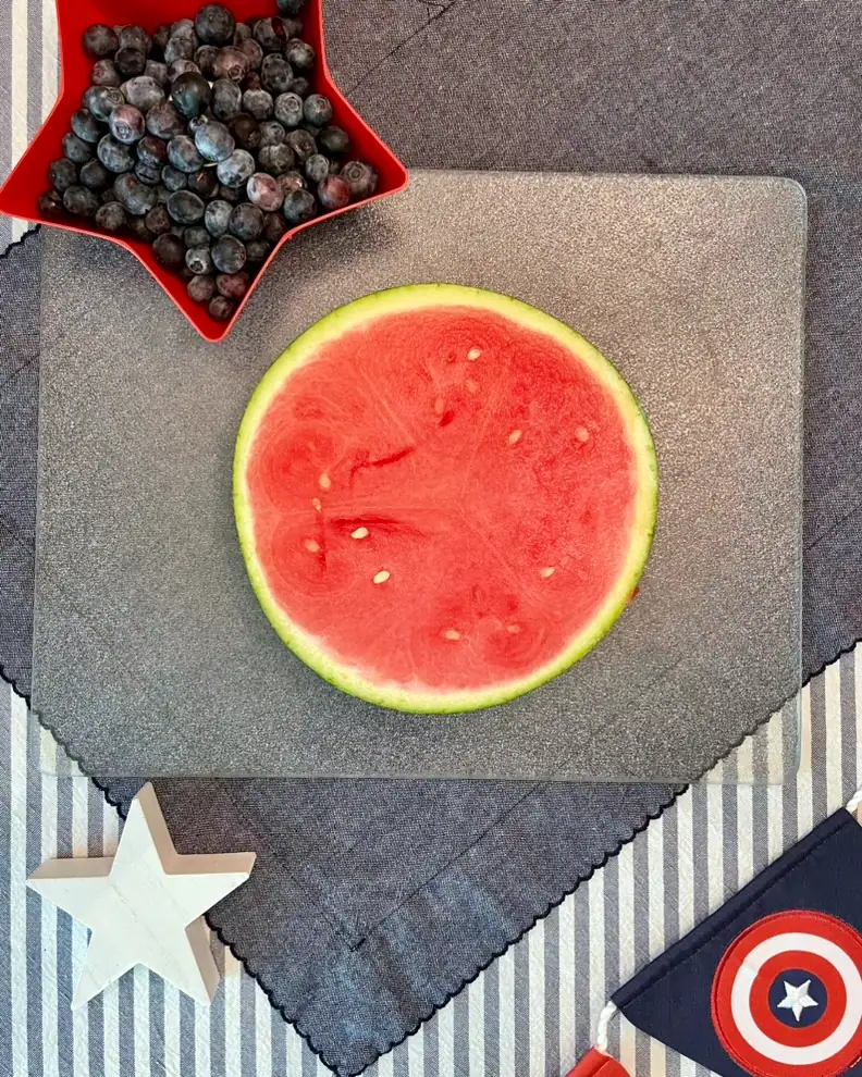 Watermelon stars and blueberries threaded onto a bamboo skewer for a red white and blue 4th of July fruit kabob recipe.