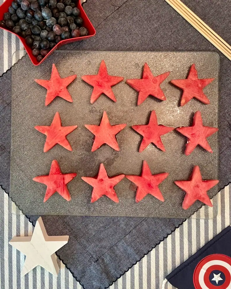 Watermelon stars and blueberries threaded onto a bamboo skewer for a red white and blue 4th of July fruit kabob recipe.