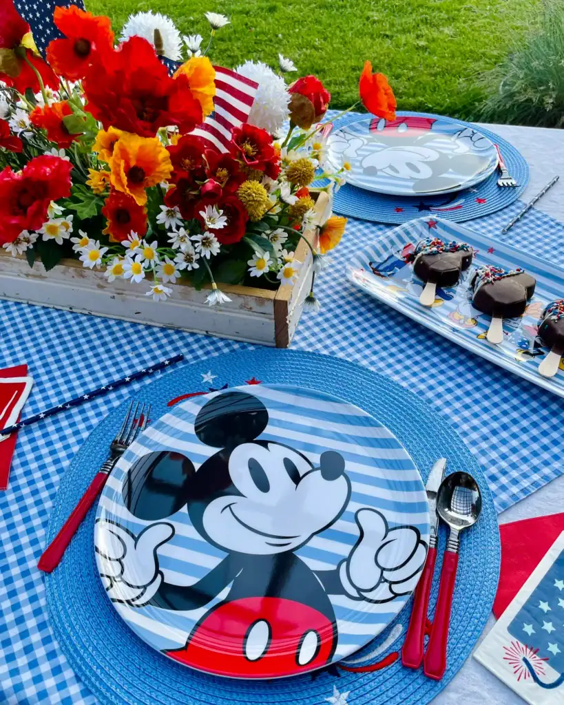 Patriotic Disney tablescape with blue gingham runner, retro Mickey plates, and wildflower centerpiece for the 4th of July