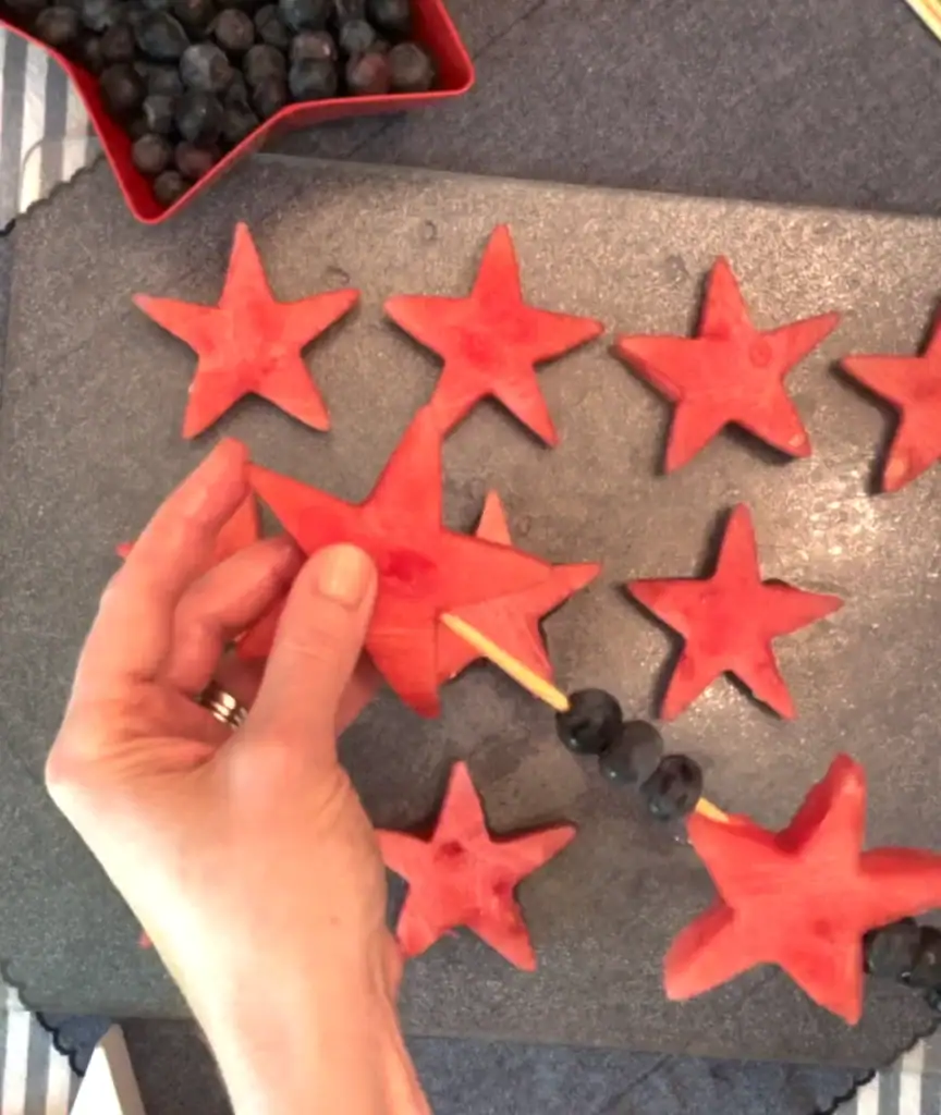 Watermelon stars and blueberries threaded onto a bamboo skewer for a red white and blue 4th of July fruit kabob recipe.